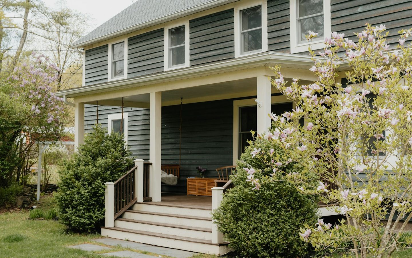 House porch with steps leading to the front door, spring shrubs in bloom
