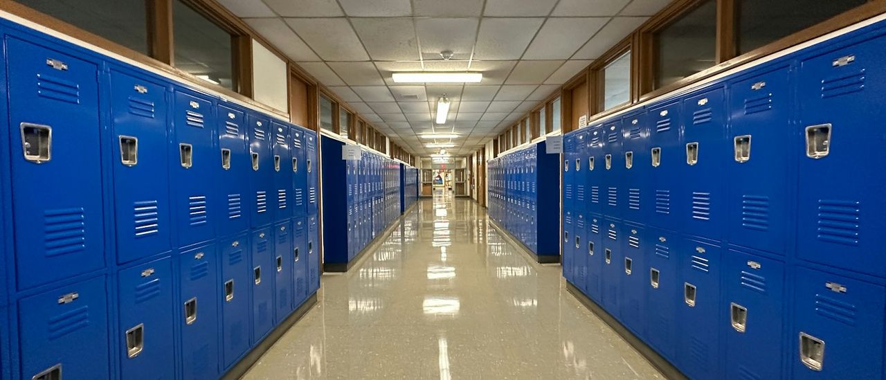 Empty school hallway lined with blue lockers