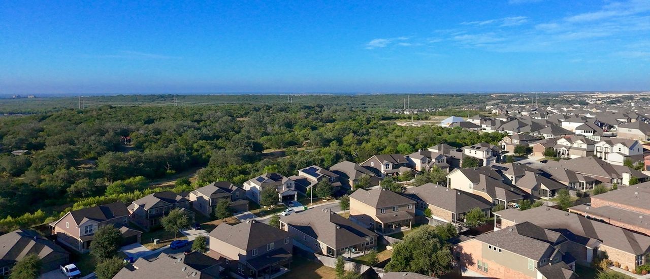 Aerial view of a suburban neighborhood beside dense green forest