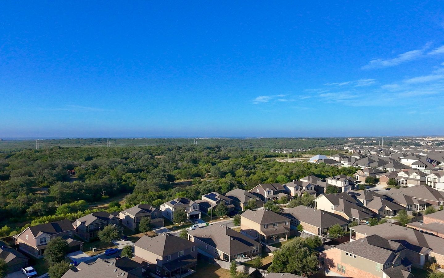 Aerial view of a suburban neighborhood beside dense green forest